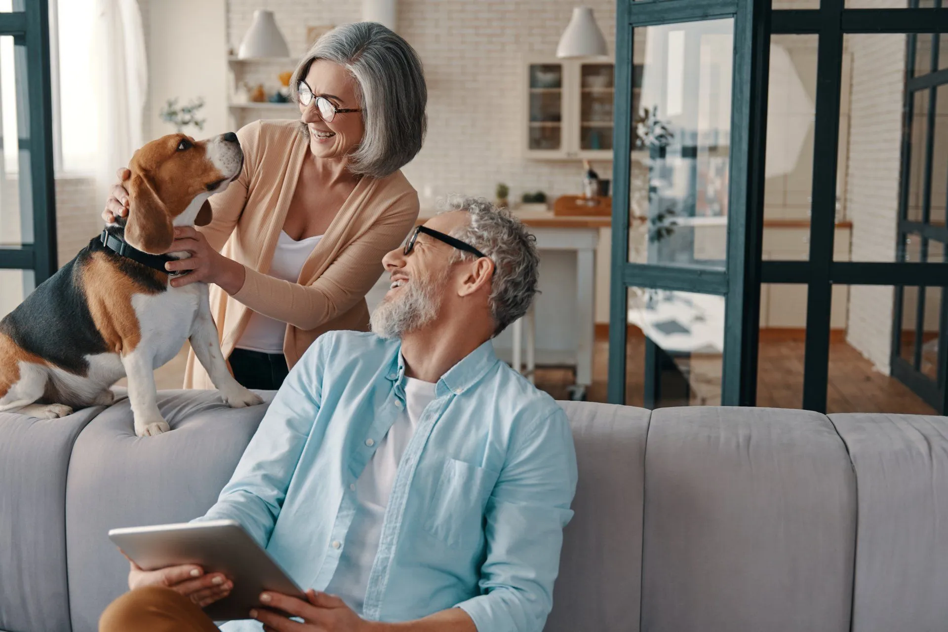 A smiling older couple relaxing at home with their beagle, enjoying conversation together